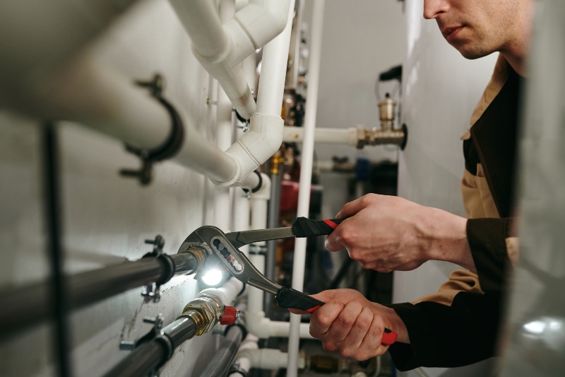 Professional plumber using heavy-duty tools on complex piping systems, showcasing Prime Plumbing Services' expertise in plumbing services for medical clinics Edmonton.